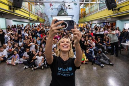 Atriz Millie Bobby Brown posando para selfie com crianças em escola de São Paulo - Metrópoles