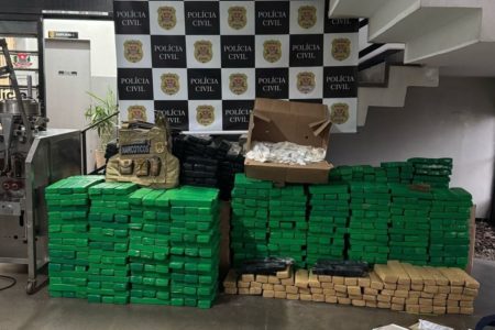 Imagem colorida de tijolos verdes de maconha agrupados em frente a uma parede da Polícia Civil - Metrópoles