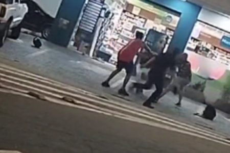 Imagem colorida de pessoas em volta de assaltante de farmácia. Metrópoles
