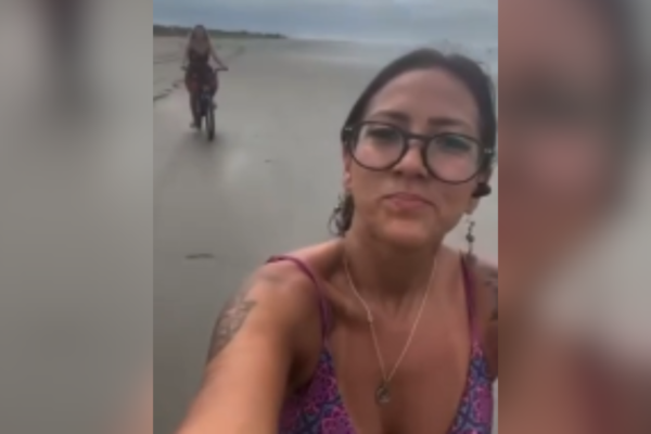 Imagem colorida de mulher andando de bicicleta. Metrópoles