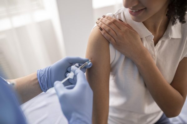 Imagem colorida de mulher sendo vacina contra Influenza