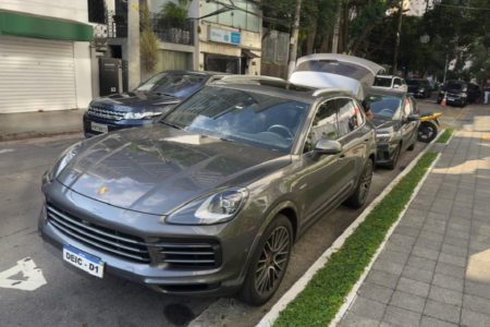 Imagem colorida mostra carro do Deic com policial checando algo no porta-malas. Polícia investiga quadrilha que usava refugiados em esquema de lavagem de dinheiro - Metrópoles
