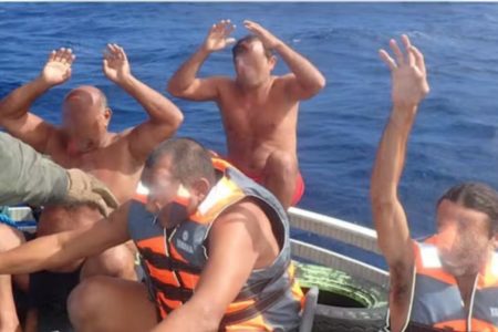 Homem sem camisa, com mãos ao alto, em barco em alto mar - Metrópoles
