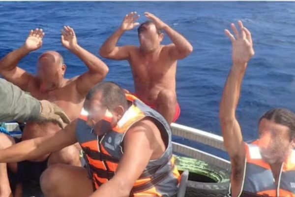 Homem sem camisa, com mãos ao alto, em barco em alto mar - Metrópoles