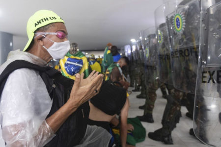 Foto colorida de bolsonaristas rezando em frente à polícia _ Metrópoles